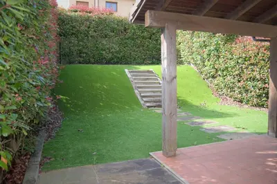 a garden with a lawn with a wooden structure at Precioso adosado en Urbanización con campo de golf in Miño