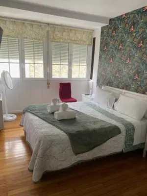 a bedroom with a large bed with a red chair at Apartamento próximo a la catedral in Santiago de Compostela