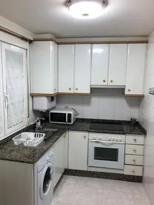 a kitchen with white cabinets and a sink and a dishwasher at Apartamento próximo a la catedral in Santiago de Compostela