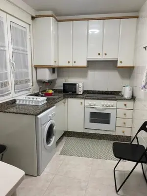 a kitchen with white cabinets and a washing machine at Apartamento próximo a la catedral in Santiago de Compostela