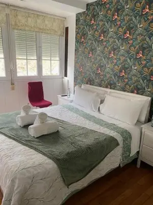 a bedroom with a large bed with a red chair at Apartamento próximo a la catedral in Santiago de Compostela