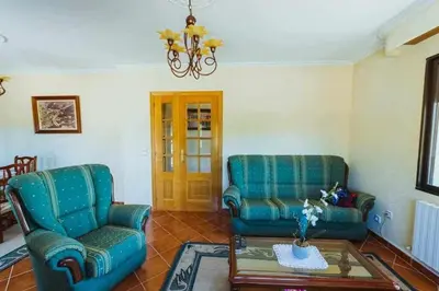 a living room with two chairs and a coffee table at Casa Ourense Guxinde in Pereira