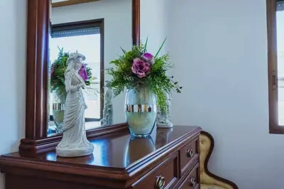 a dresser with a mirror and a vase with flowers on it at Casa Ourense Guxinde in Pereira