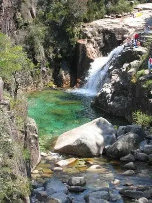 a waterfall in a river with green water and rocks at Casa Ourense Guxinde in Pereira