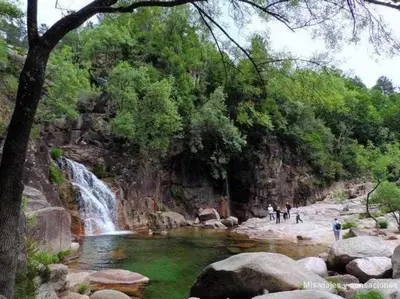 people standing in a pool of water next to a waterfall at Casa Ourense Guxinde in Pereira