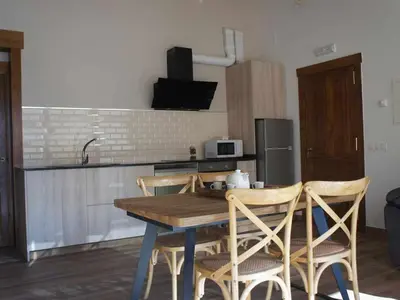 a kitchen with a wooden table and some chairs at O Fogón - Casa Ferrador (Ribeira Sacra) in Sober