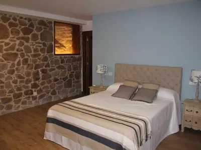 a bedroom with a bed and a stone wall at O Fogón - Casa Ferrador (Ribeira Sacra) in Sober