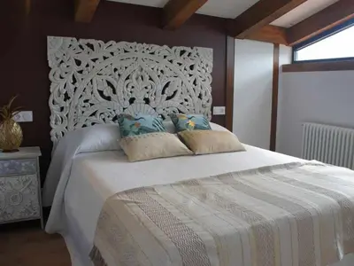 a bedroom with a large bed with a white headboard at O Yunque - Casa Ferrador (Ribeira Sacra) in Sober