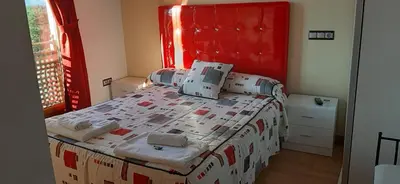 a bedroom with a large bed with a red headboard at Casa Rural FULGUERA in El Espino