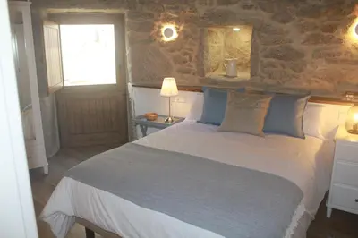 a bedroom with a bed and a stone wall at O XARDÍN DA FRAGA in A Lama