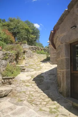 a stone path next to a building with a door at O XARDÍN DA FRAGA in A Lama
