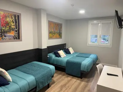a room with two beds and a table at Pension San Anton in Melide