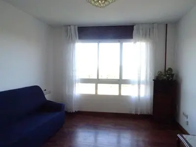 a living room with a blue couch and a large window at La Casa de Vicenta in Arzúa