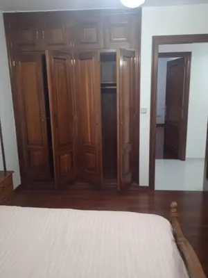 a bedroom with wooden cabinets and a bed and a mirror at La Casa de Vicenta in Arzúa