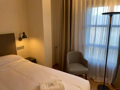 a bedroom with a bed and a chair and a window at Hotel San Marcus in Porta