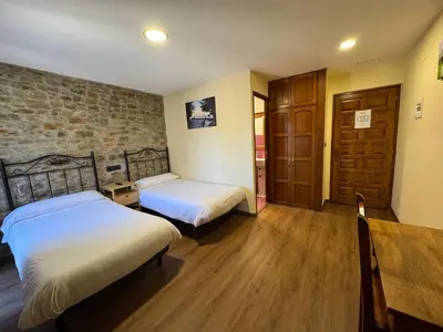 two twin beds in a room with a fireplace at Casa O Cebreiro in O Cebreiro