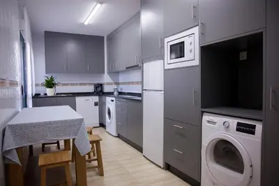 a kitchen with a table and a washing machine at Laros Pios Alojamiento 2 in Villalba