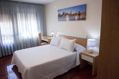 a hotel room with a white bed and a window at Laros Pios Alojamiento 2 in Villalba
