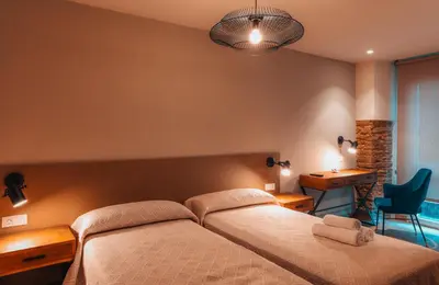 a bedroom with a bed and a desk and a chair at Pensión A Marronda in Baleira