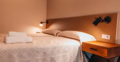 a bedroom with a large bed and a wooden table at Pensión A Marronda in Baleira