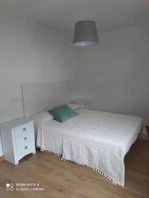 a bedroom with a white bed and a night stand at Piso de alquiler en Tapia de Casariego in Tapia de Casariego