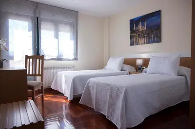 a bedroom with two beds with white linens at Laros Pios Alojamiento 1 in Villalba