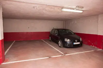 a black car parked in a garage with red walls at Laros Pios Alojamiento 1 in Villalba