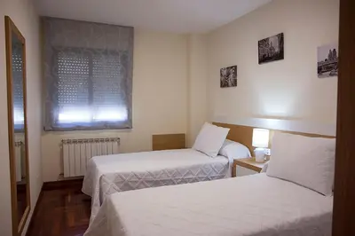 a hotel room with two beds and a window at Laros Pios Alojamiento 1 in Villalba