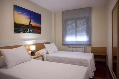 a hotel room with two beds and a window at Laros Pios Alojamiento 1 in Villalba