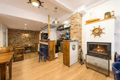 a living room with a fireplace and a bar at Hotel A Falúa in Puentedeume