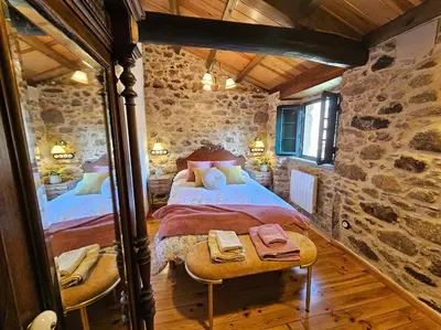 a bedroom with two beds and a stone wall at A Casa dos Avós - Vilariño - A Coruña in Vilariño