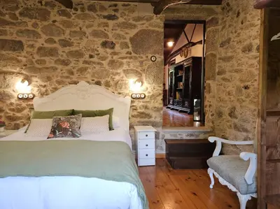 a bedroom with a bed and a stone wall at A Casa dos Avós - Vilariño - A Coruña in Vilariño