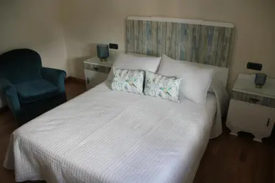 a bedroom with a large white bed with a blue chair at Casa Sueño in Foz
