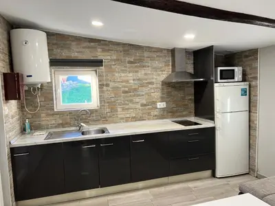 a kitchen with black cabinets and a white refrigerator at Casa rural La casilla de Ois-Betanzos-A Coruña in Coirós