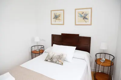 a bedroom with a bed with white sheets and two tables at Casa Muiño dos Frades in Lourenzá