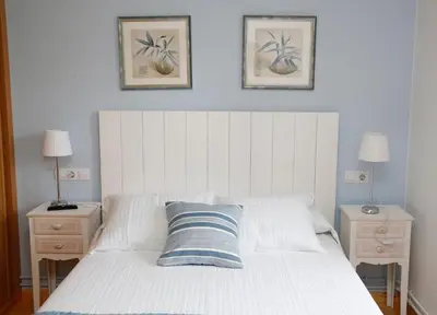 a bedroom with a white bed with two nightstands and two pictures at Casa Muiño dos Frades in Lourenzá