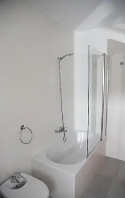 a white bathroom with a shower and a toilet at Casa Muiño dos Frades in Lourenzá