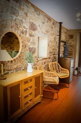 a room with a stone wall with a table and chairs at Miña Nai, Casa Rural in Lalín