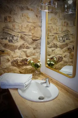 a bathroom with a sink and a stone wall at Miña Nai, Casa Rural in Lalín