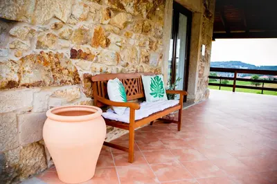 a bench sitting on a porch with a vase at Miña Nai, Casa Rural in Lalín