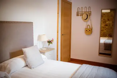 a bedroom with a white bed and a mirror at Miña Nai, Casa Rural in Lalín