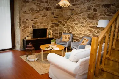a living room with a white couch and chairs and a tv at Miña Nai, Casa Rural in Lalín