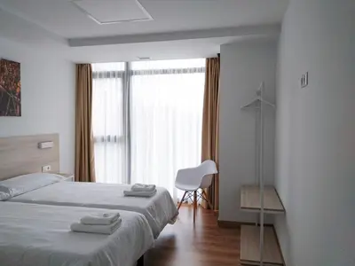 a bedroom with a bed and a chair and a window at Vía Sacra in Porta
