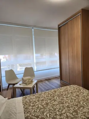 a bedroom with a bed and two chairs and windows at Hospedaje Norte in Puentedeume