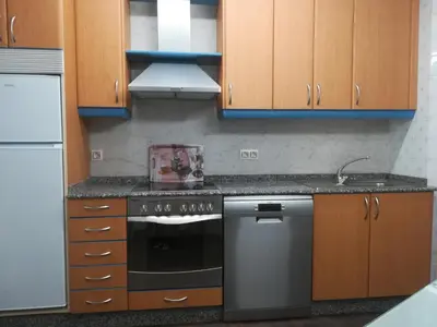 a kitchen with wooden cabinets and a stove top oven at PISO XUNQUEIRA in Viveiro