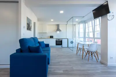 a living room with a blue couch and a table at MIRADOR DE LA MURALLA in Betanzos