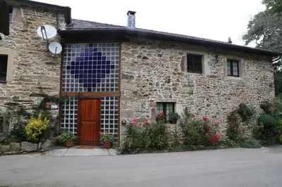 a stone house with a red door and flowers at Casa Rural Madreselva in Navelgas