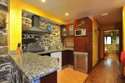 a kitchen with wooden cabinets and a stone wall at Casa Rural Madreselva in Navelgas