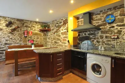 a kitchen with stone walls and a washer and dryer at Casa Rural Madreselva in Navelgas