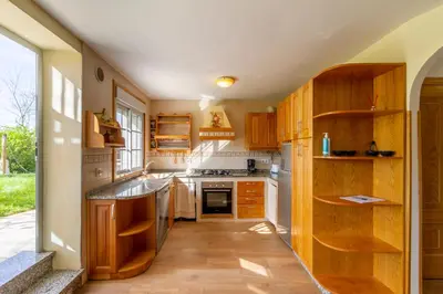 a kitchen with wooden cabinets and a large window at CASA NIDES in Doade